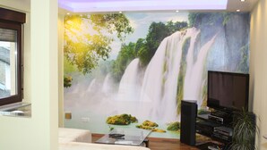Un salon agrémenté d’une grande fresque représentant une cascade, d’un téléviseur à écran plat et d’un système audio.