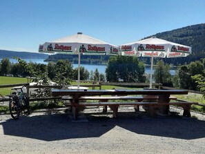 Ein malerischer Außenbereich mit Picknicktischen und Sonnenschirmen, beschriftet mit 'Rothaus'.