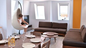 En moderne stue med en brun sofa, et spisebord med tallerkener og glas, og en hængekøjsstol.
