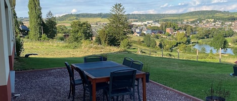 Enjoy al fresco dining with a scenic view of the town from this outdoor patio, featuring a table and chairs.