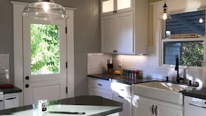 A kitchen with white cabinets, a black countertop, and pendant lighting.