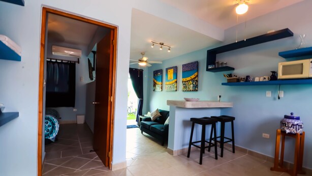 Un espacio habitable compacto con kitchenette, sofá y comedor.