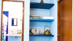 Un baño con lavamanos, espejo y estantería azul.