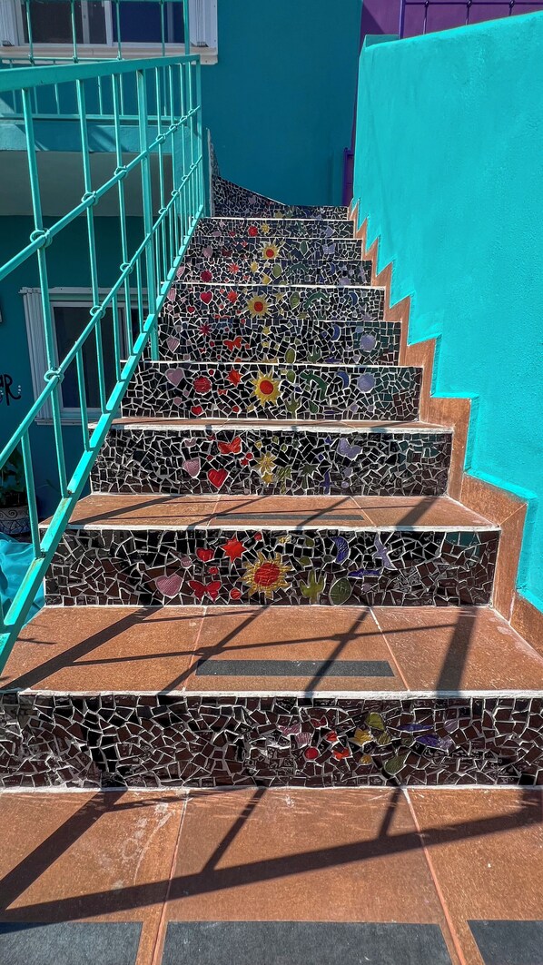 A staircase with mosaic tiles and a teal railing.
