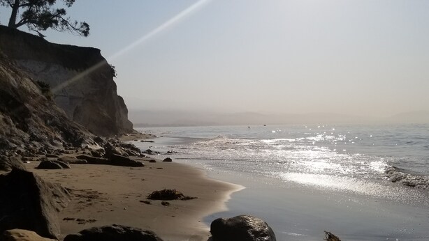Ein Strand mit felsigem Gelände und einer Klippe.