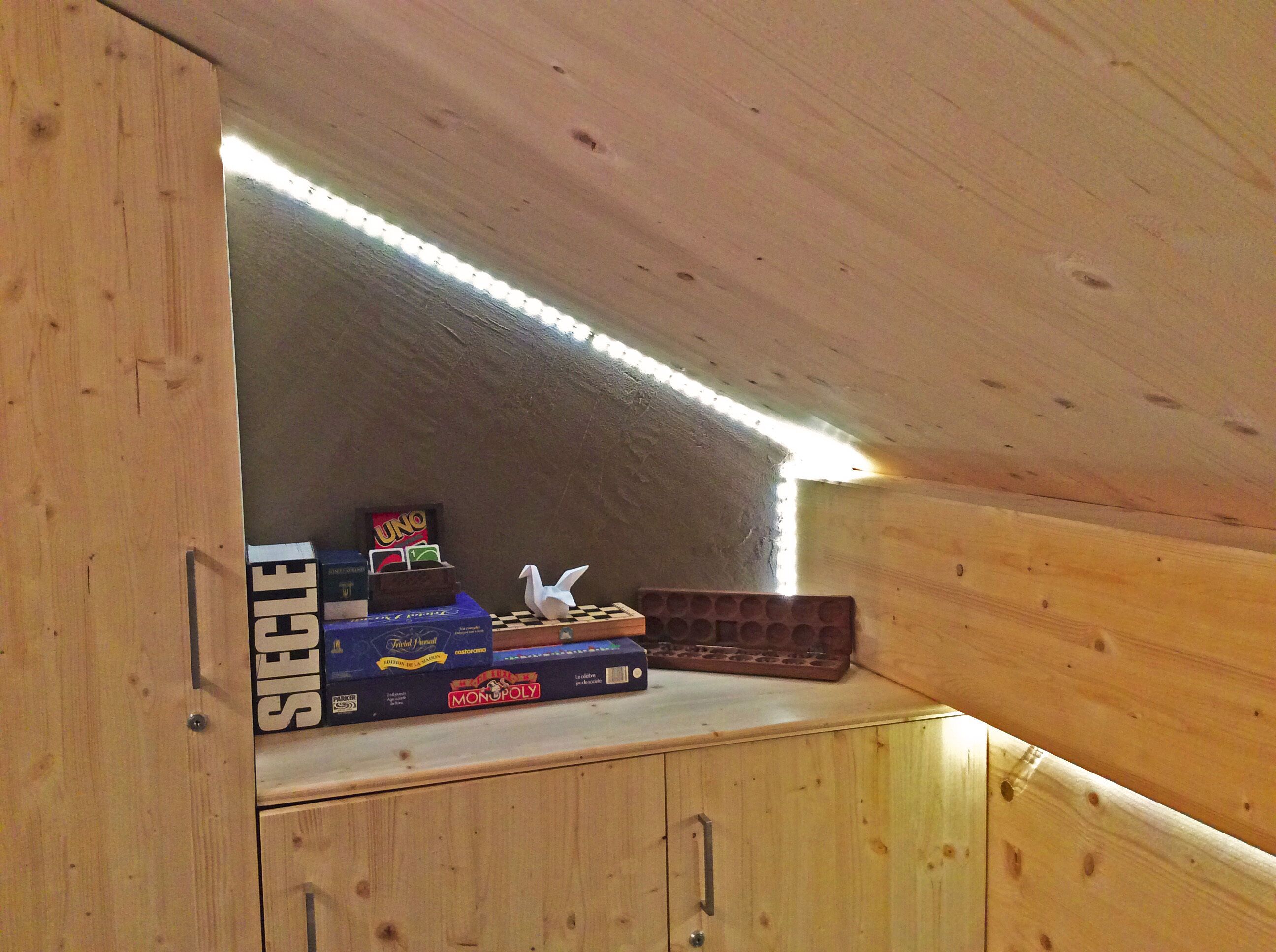 Ein Holzschrank mit geneigter Ablagefläche, der Brettspiele wie UNO und Monopoly beherbergt.