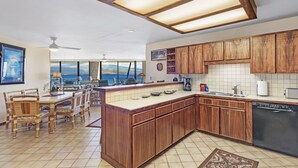 Una cucina moderna con mobili in legno, un'isola centrale e vista sull'oceano.