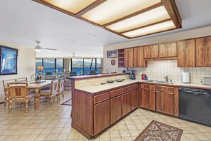 A modern kitchen with wooden cabinets, a central island, and a view of the ocean.