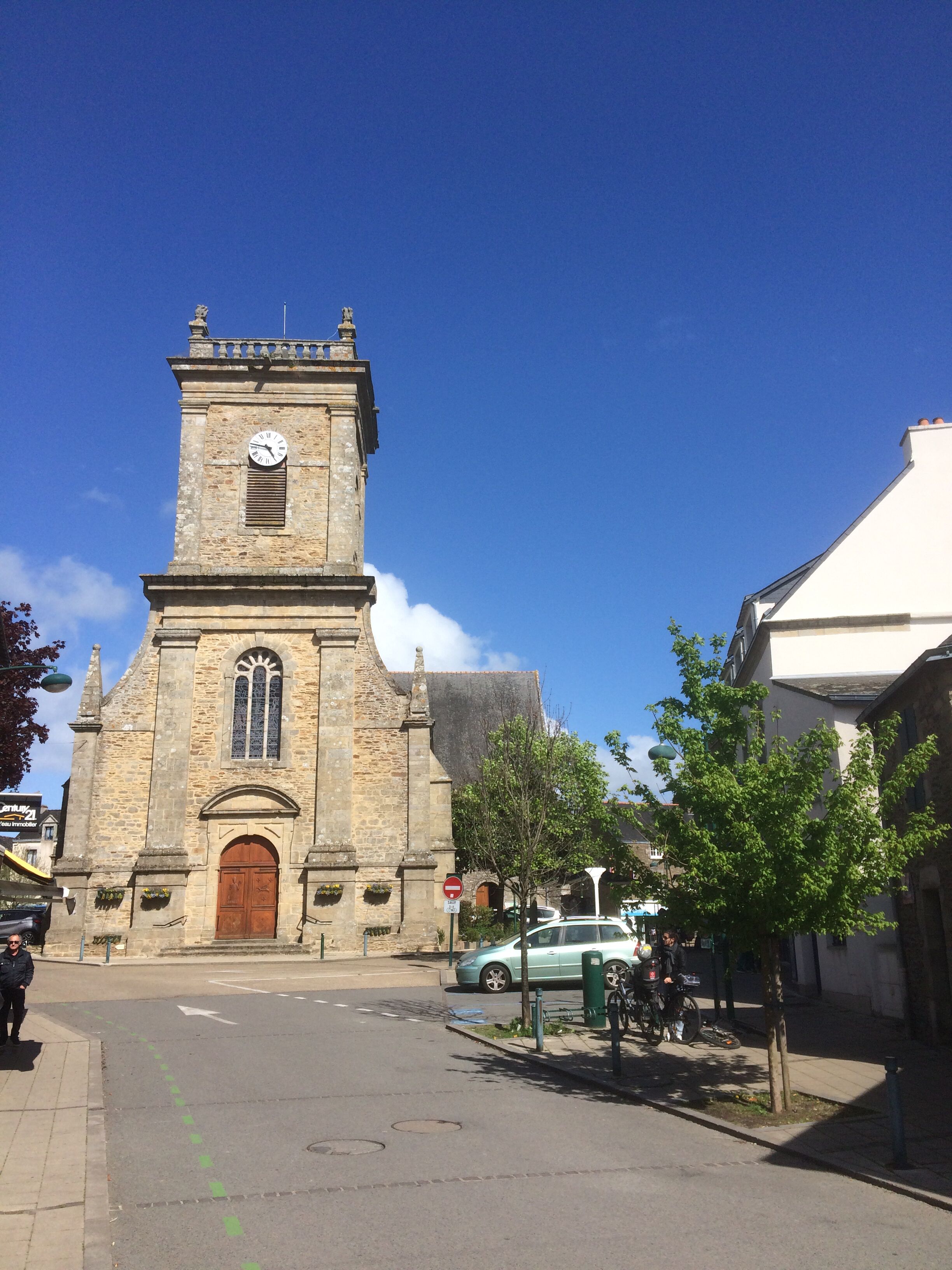 A historic stone church with a clock tower, a large wooden door, and a clear blue sky.