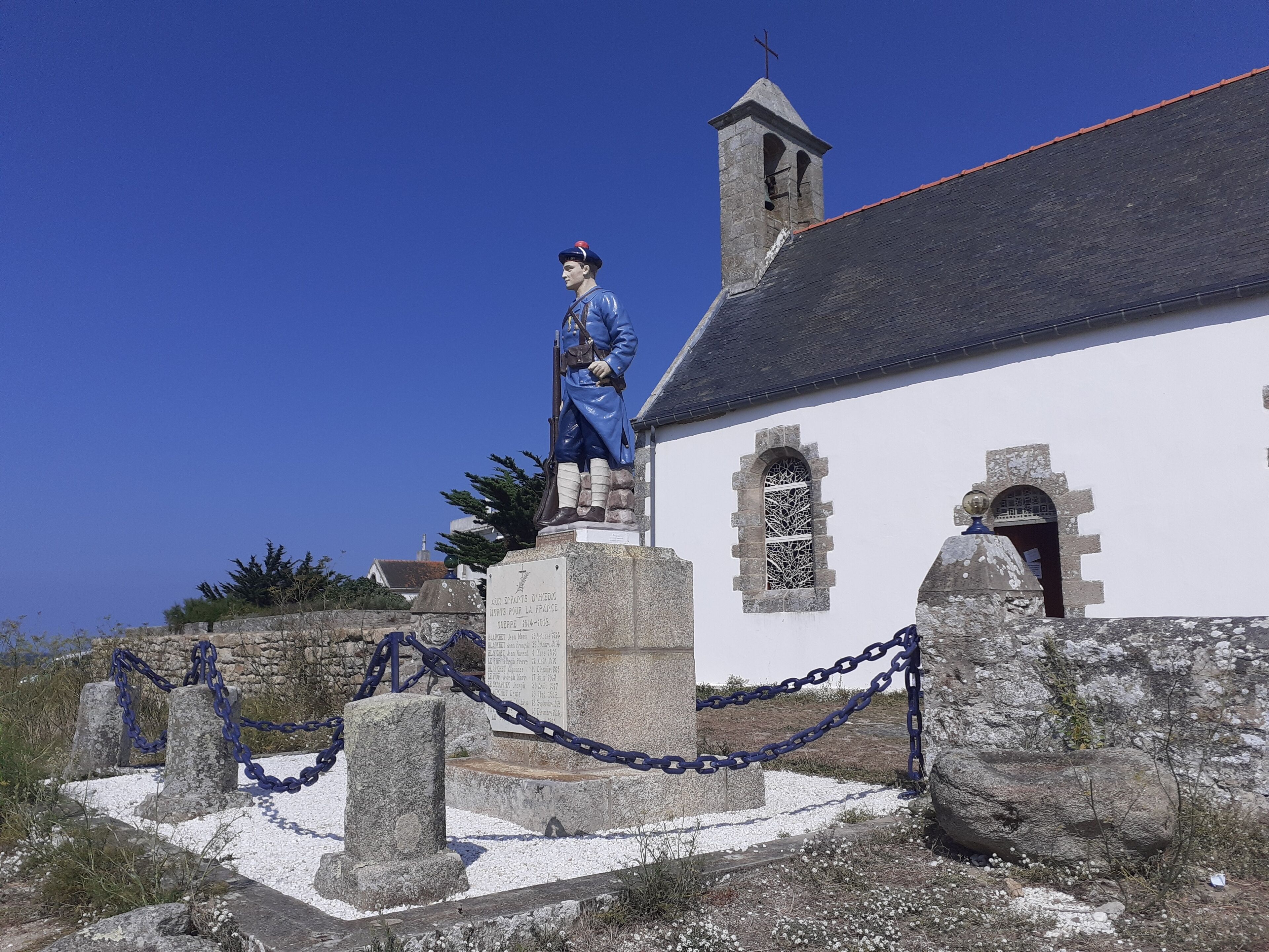 Una estatua de un soldado sobre un pedestal, con una iglesia al fondo.