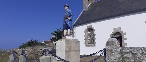 Una estatua de un soldado sobre un pedestal, con una iglesia al fondo.