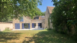 A stone house with a patio, large windows, and a door. - Large independent house in the village center with large garden.  (Soisy-sur-École)