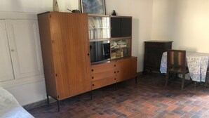 A room with a wooden cabinet, a table with a floral tablecloth, and a chair. - Large independent house in the village center with large garden.  (Soisy-sur-École)