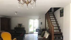 A spacious living area with a staircase, a chandelier, and a view through a glass door. - Large independent house in the village center with large garden.  (Soisy-sur-École)