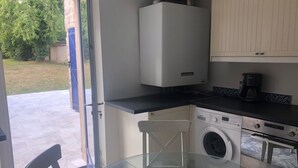 A compact kitchen with a washing machine, a coffee maker, and a glass table. - Large independent house in the village center with large garden.  (Soisy-sur-École)