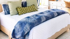 Ein Bett mit einer weiß-blauen Bettdecke, mehreren Kissen und einem gerahmten Bild darüber.