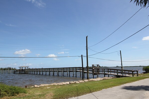 A wooden pier extending into a body of water, with a small shelter at the end.