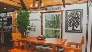 Una mesa de comedor de madera con sillas, una planta en maceta y una ventana que da a un bosque.