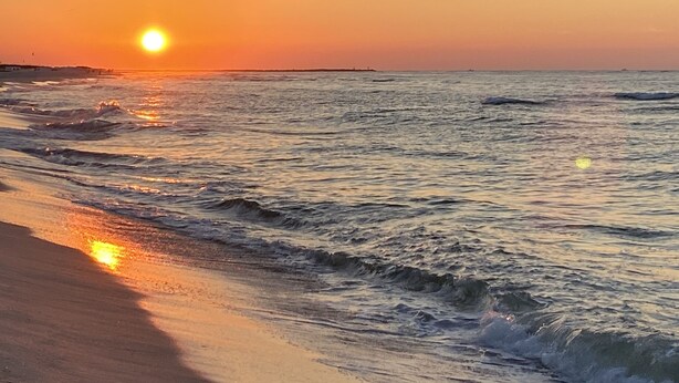 Una playa con olas y un atardecer.