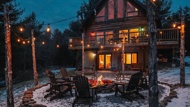 A cabin with a fire pit, outdoor seating, and string lights. - 5BR Catskills Retreat • Ski Close • Hot Tub, Firepit, 2 grills, Deck, Fast WiFi (Prattsville)
