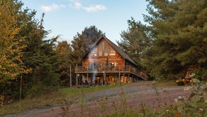 A rustic cabin with a large porch, surrounded by dense forest. - 5BR Catskills Retreat • Ski Close • Hot Tub, Firepit, 2 grills, Deck, Fast WiFi (Prattsville)