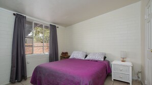 Une chambre à coucher avec un lit, des rideaux, une table de chevet et une fenêtre.