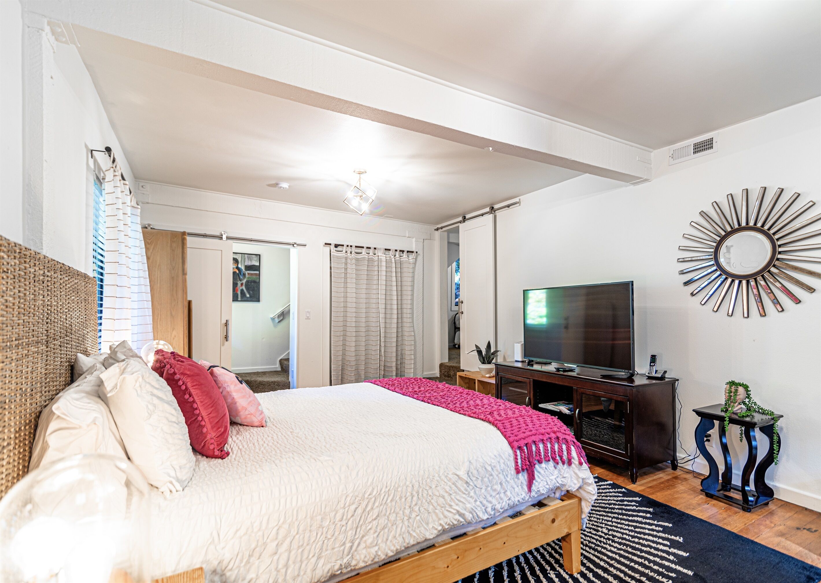 Una camera da letto con un letto, una televisione, uno specchio e una scala che conduce a un'altra stanza.