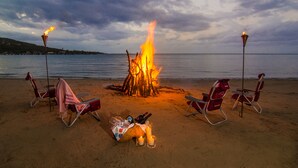 Escena de playa con un hogar para fuego rodeado de sillas y una manta.