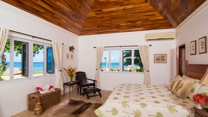 Un dormitorio con cama, una silla, una mesa y vista al mar.