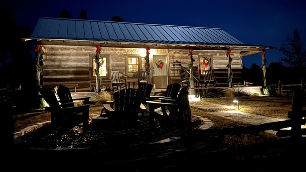 A rustic cabin with a porch, outdoor seating, and a sign reading "The Green Mountain Inn".