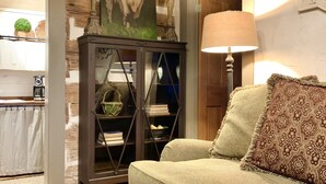 A cozy living room with a green sofa, a decorative lamp, a wooden cabinet, and a painting of a cow.