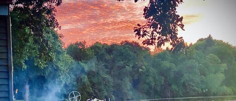 A lakeside view with a fire pit, docked boats, and a grassy area.