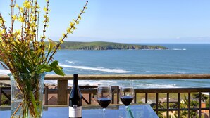 Une table avec une bouteille de vin et deux verres, donnant sur l’océan.