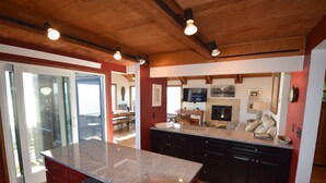 Une cuisine moderne avec des plans de travail en granit, des meubles de couleur sombre et un plafond en bois.