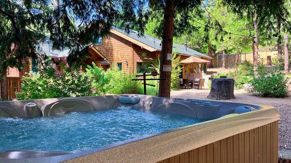 Un jacuzzi rodeado por una terraza de madera, con un edificio rústico al fondo.