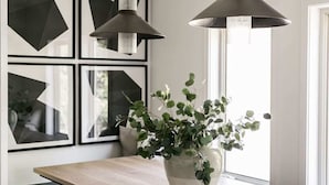 Cozinha moderna com ilha de madeira, cadeiras pretas e luminárias pendentes.