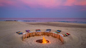 Une plage avec un foyer et des couvertures colorées.