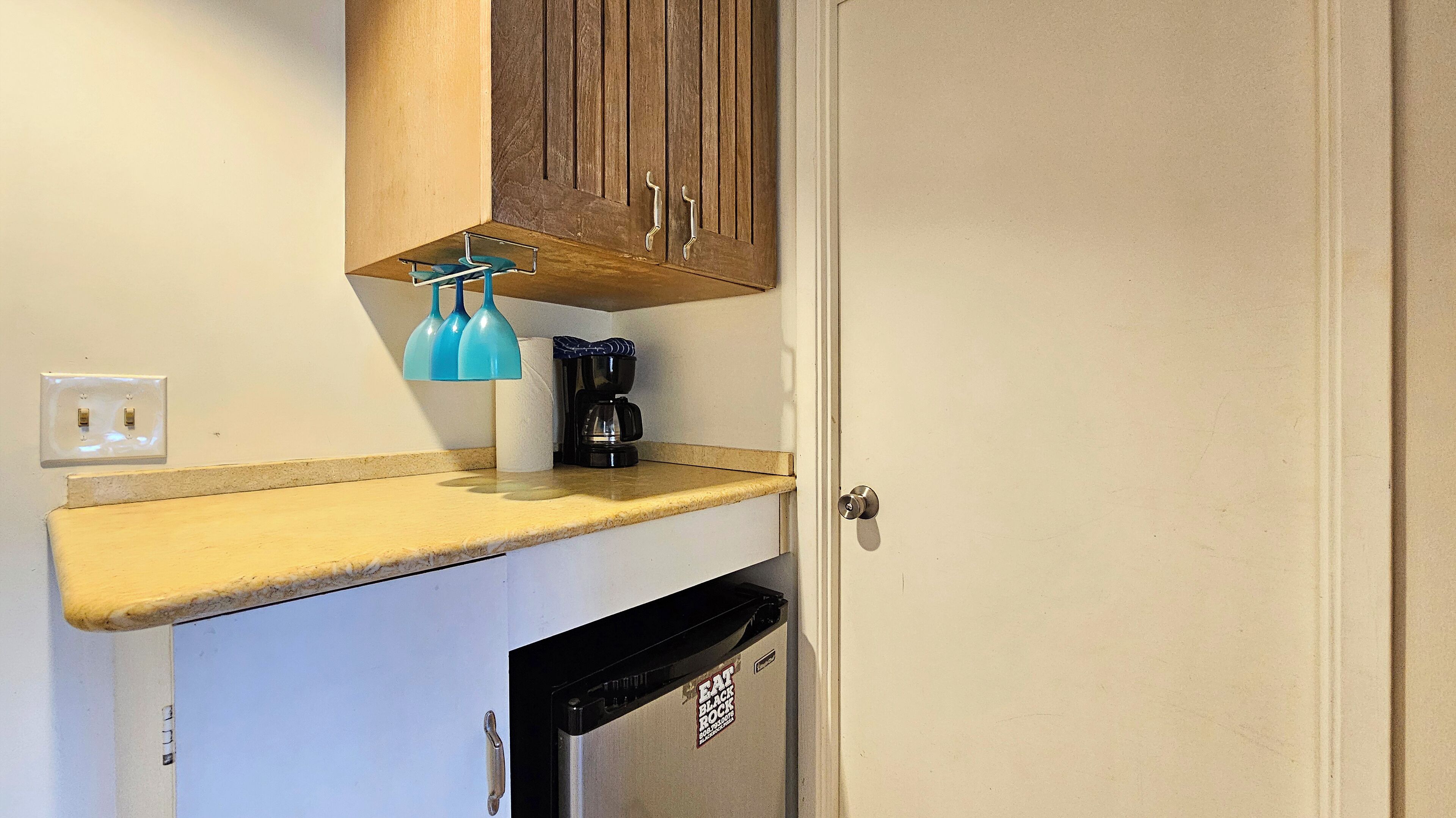 Cocina compacta con lavavajillas integrado, cafetera y dispensador de toallas.