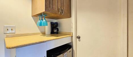 Cocina compacta con lavavajillas integrado, cafetera y dispensador de toallas.