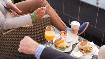 A dining table with a meal, a glass of orange juice, and a Starbucks coffee cup.
