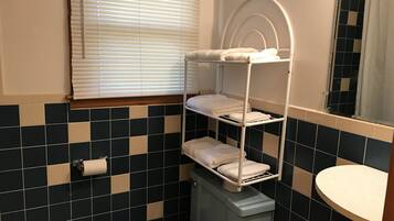 A bathroom with a tiled floor, a toilet, a sink, and a window with blinds.