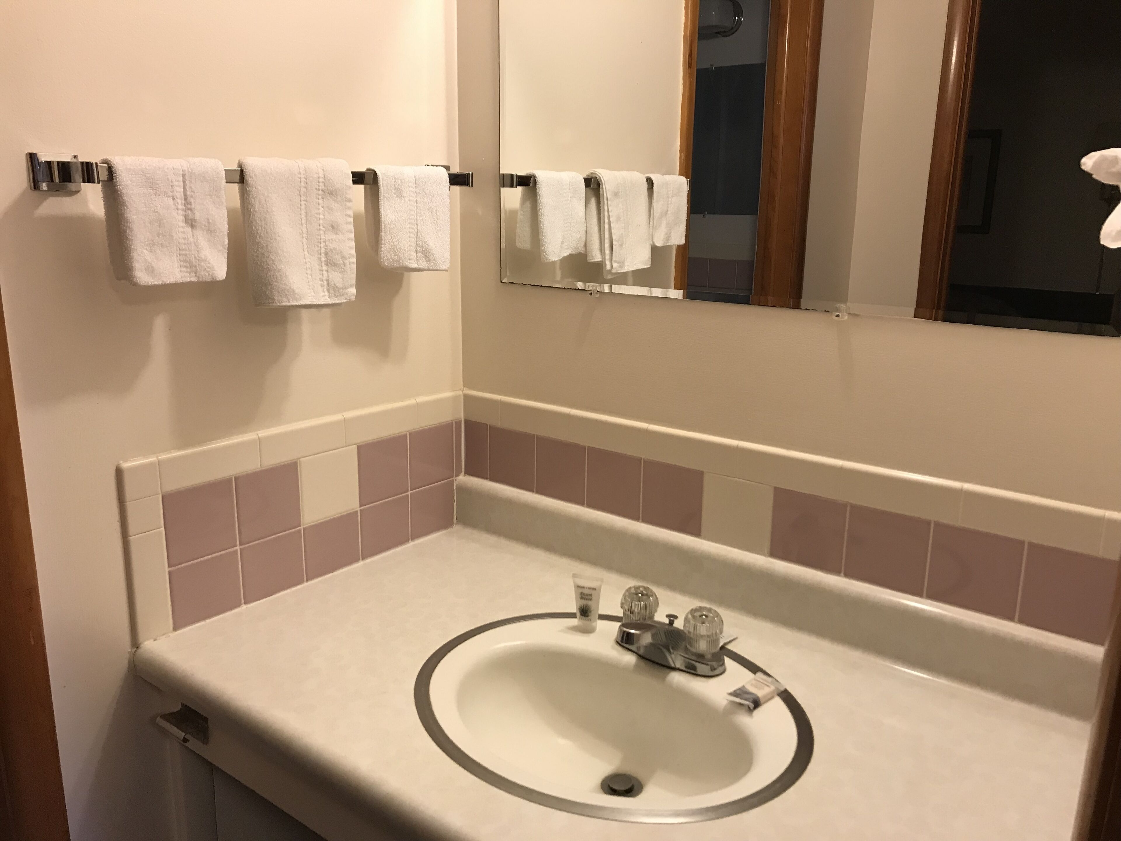 A bathroom with a sink, mirror, and towels on a rack.