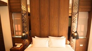Ein großes Bett mit weißen Leinen und aufgerollten Handtüchern in einem Hotelzimmer mit Holzwänden und zwei Nachttischlampen.