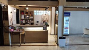 Ein Empfangstresen mit Theke, Regale mit verschiedenen Gegenständen und ein Kühlschrank im Hintergrund.