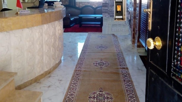 Un hall de hotel con una recepción, una zona de estar, una chimenea y una alfombra estampada.