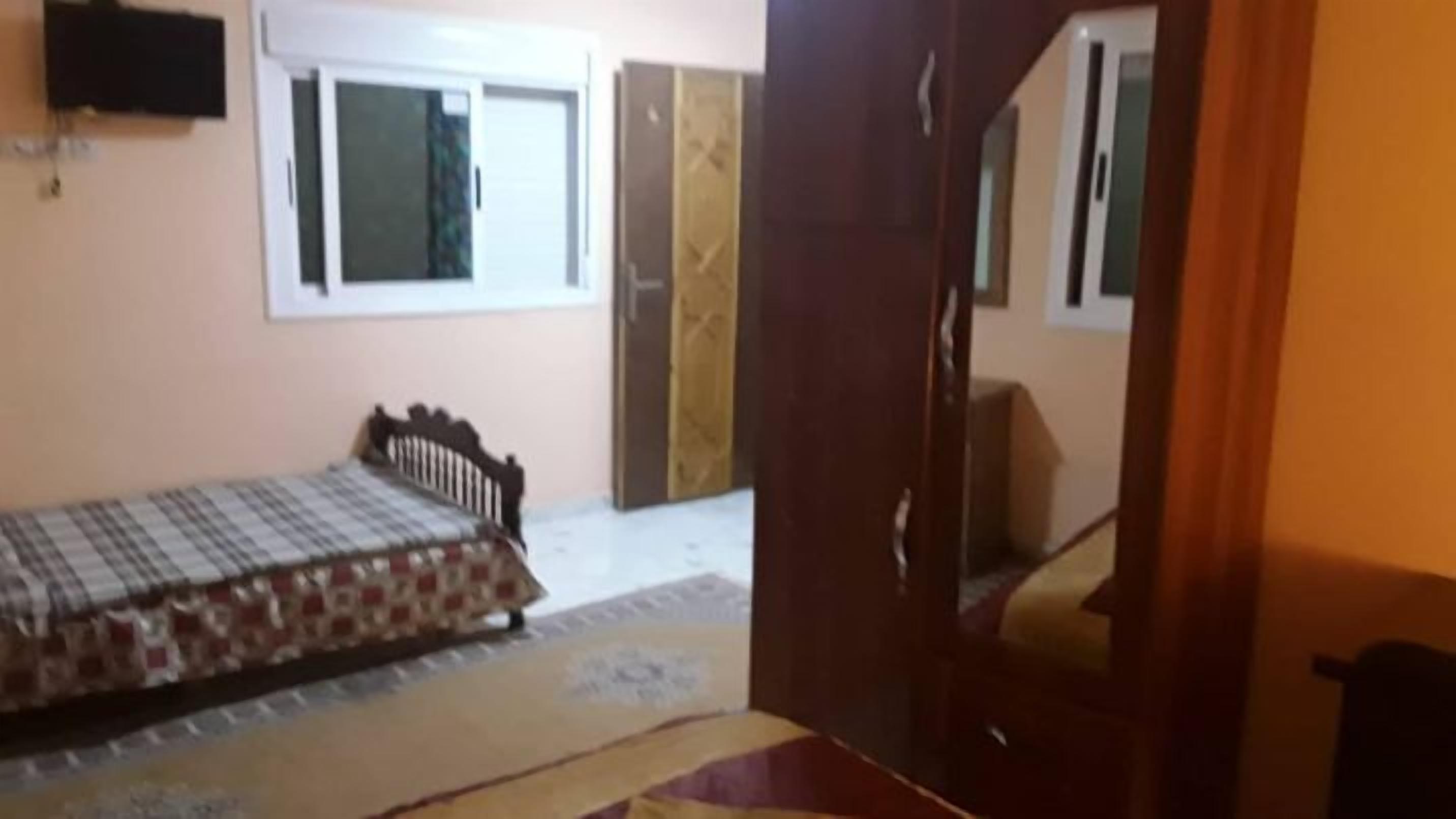 A bedroom with a bed, a window, and a door.