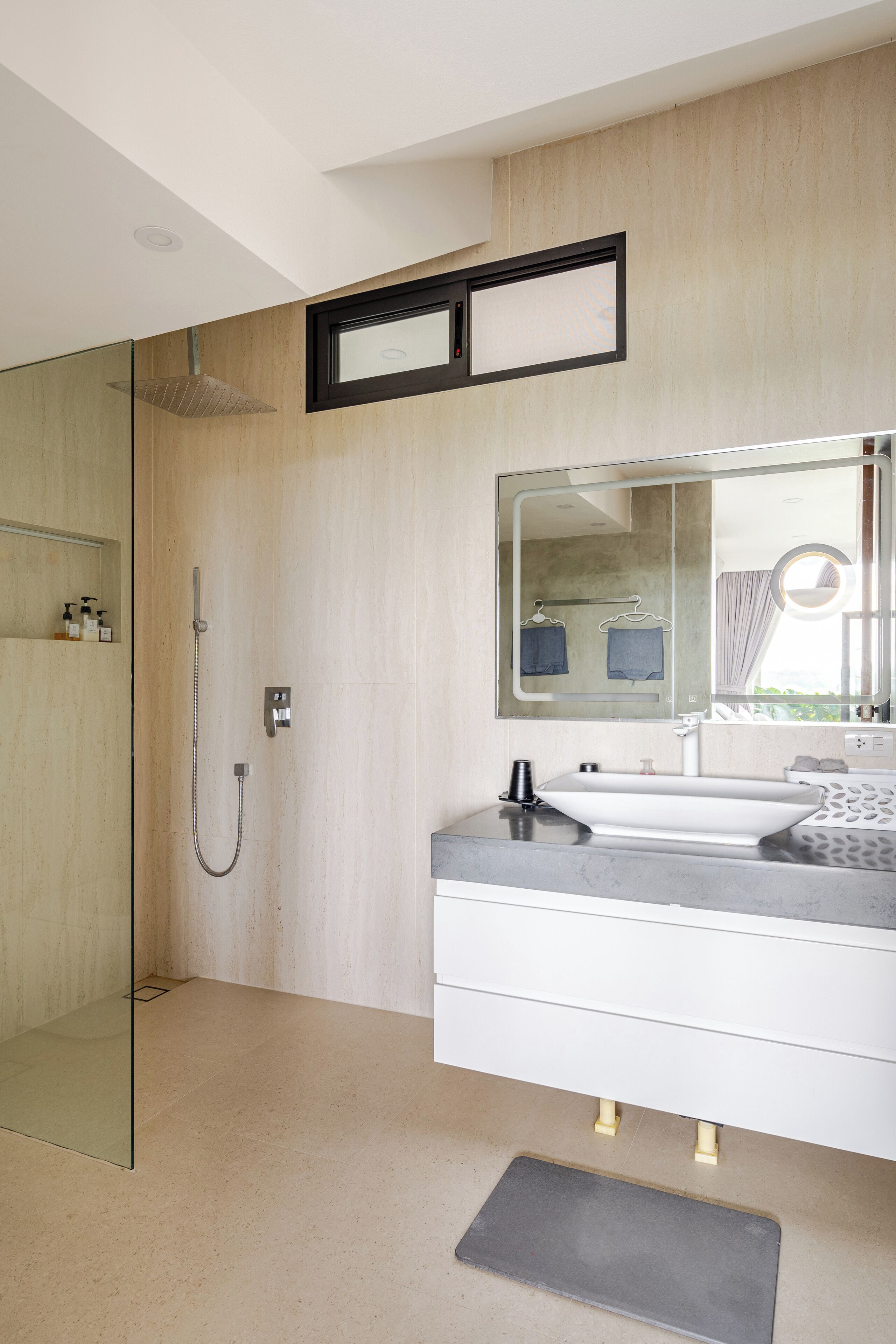 A modern bathroom with a glass shower enclosure, a large mirror, and a white vanity.
