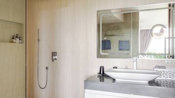 A modern bathroom with a glass shower enclosure, a large mirror, and a white vanity.
