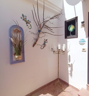 Um corredor decorado com um galho ornamental, um candelabro e uma placa de boas-vindas.