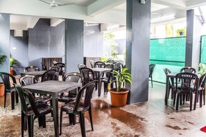 Enjoy meals in a stylish dining area with tables and chairs in an open layout, surrounded by lush greenery and polished flooring.
